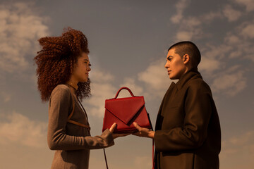 Two women holding a classic red handbag