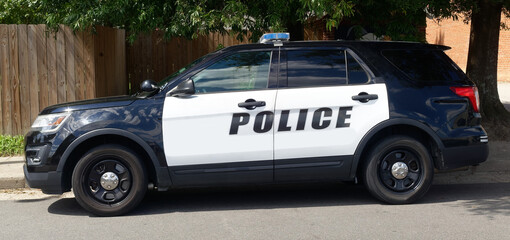 Sided view of police SUV parked in residential neighborhood. © Noel