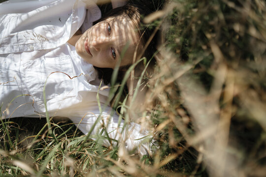 young woman resting lying in tall grass