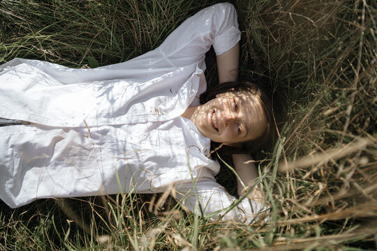 young laughing woman lies in the grass in nature