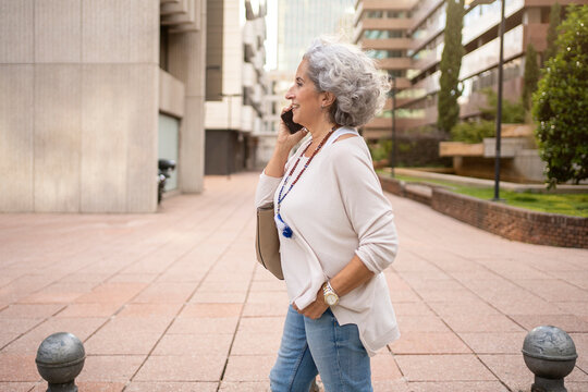 Side view of mature woman talking with her cell phone in an urban area