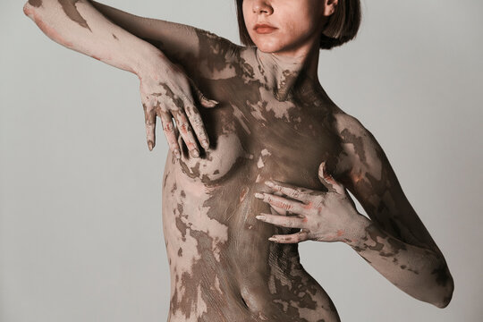 Crop female model touching muddy breasts