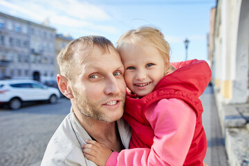 Mature Caucasian man and little smiling girl in his arms.