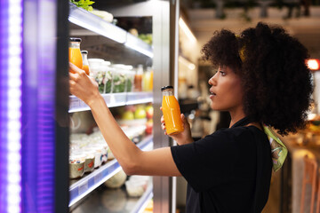 Black woman choosing juice in supermarket