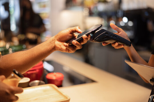 Crop client making contactless payment on POS terminal in cafe