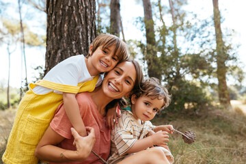 Loving mother with children embracing in countryside woods
