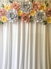 Backdrop of pastel faux flowers above curtains.