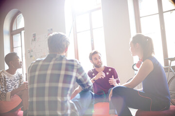 Naklejka premium Casual business people meeting in circle in sunny office