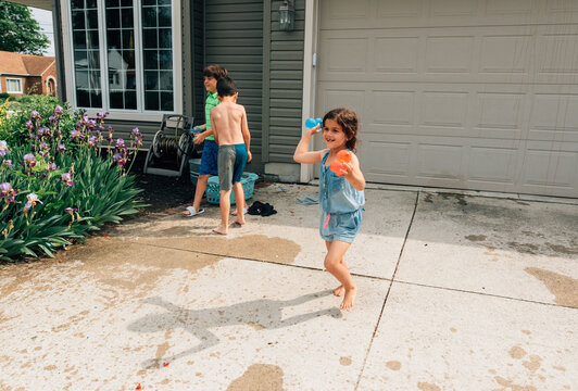 Girl laughing and chasing someone with a water balloon. 