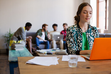 Smiling creative businesswomen working at laptop in office