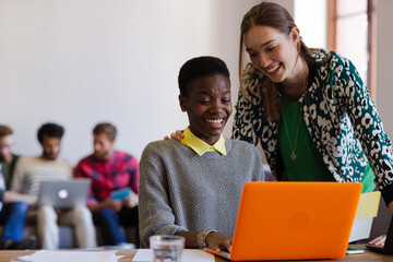 Smiling creative businesswomen working at laptop in office