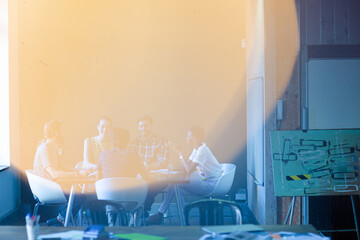 Lens flare over creative business people meeting at office table