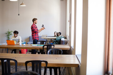 Creative businessman posing photograph for coworker instant camera in office