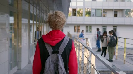 Follow shot of teen schoolboy with backpack walking outdoors