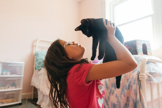 Child holding cat up in the air. 