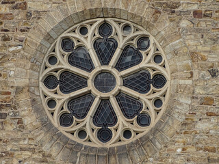 Extravagant gothic style circular window on the brick wall of a medieval monastery