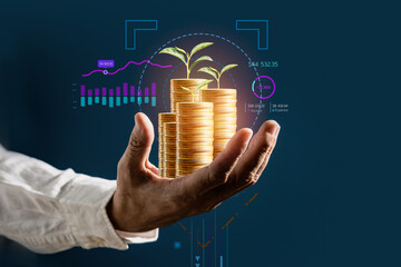 Businessman hold gold money coins with growing business graph and analysis financial data on...
