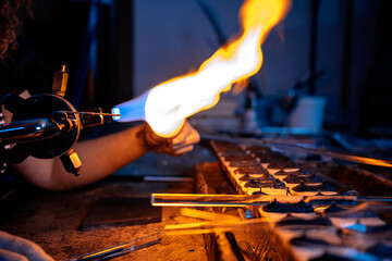 Close-up of the torch flame of a glassblower working with glass tube