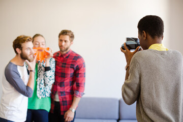 Creative business people playfully posing for coworker instant camera
