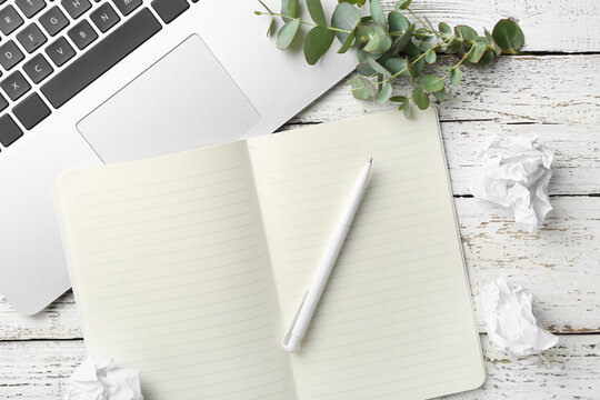 Composition with notebook, pen, laptop and crumpled paper on light wooden background
