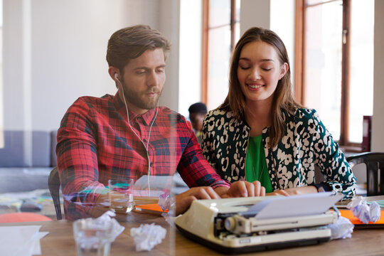 Creative writer with headphones using typewriter in office