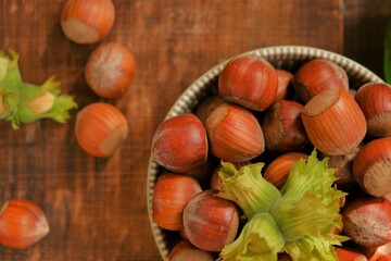 Hazelnut close-up.Nuts abundance. Ripe nuts plate and green nuts with leaves on wooden background. High quality photo