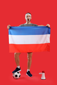 Sport fan with ball, flag and megaphone on color background