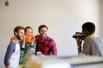 Creative business people playfully posing for coworker instant camera