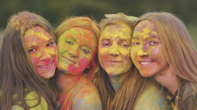 Cheerful girls posing smeared in multi-colored powder. Close-up faces.