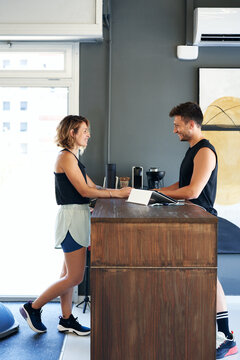 Smiling Client Talking To Coach At Reception Counter