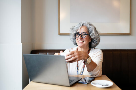 Mature woman using laptop and drinking coffee in a cafe