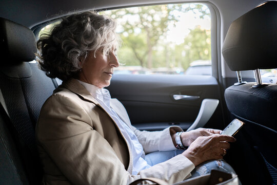Mature woman using her cell phone inside a car