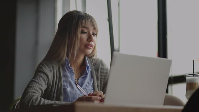 Thoughtful concerned chinese, japan, japanese, korean woman working on laptop computer looking away thinking solving problem, serious woman search for inspiration make decision feel lack of ideas