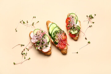 Tasty croissants with vegetables and micro green on color background