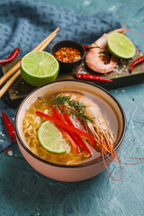 Bowl of tasty Thai soup with shrimps on color background