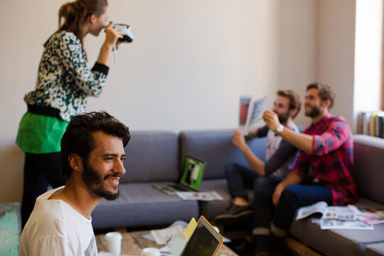 Creative business people playfully posing for coworker instant camera