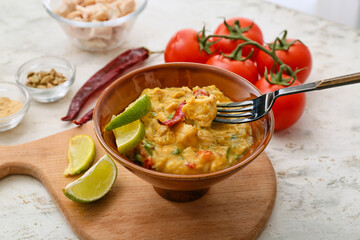 Bowl of tasty chicken curry on light background
