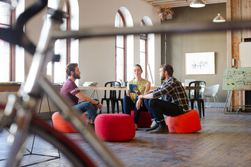 Creative business people working behind bicycle wheel in office
