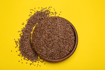 Bowl with flax seeds on color background