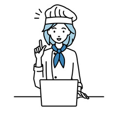 デスクで座ってPCを開いて何かひらめいた調理師の女性
