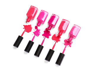 Overturned bottles of nail polishes with brushes and blots on white background