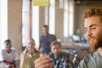 Obraz premium Casual businessman explaining diagram on glass in meeting