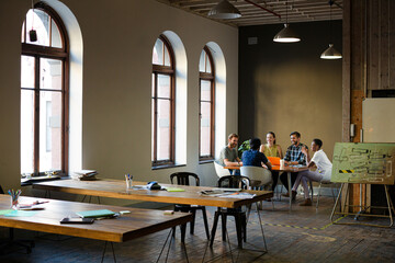 Creative business people working at tables in sunny office