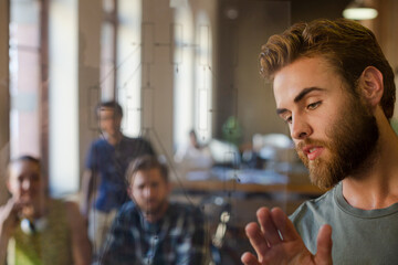 Casual businessman explaining diagram on glass in meeting