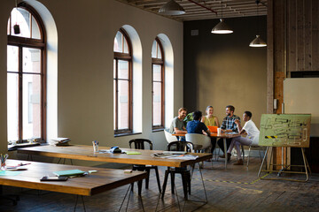 Creative business people working at tables in sunny office