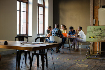 Creative business people working at tables in sunny office