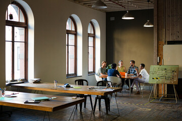 Creative business people working at tables in sunny office