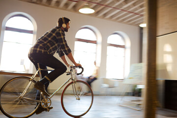 Casual businessman riding bicycle in open office