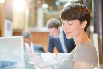 Smiling businesswoman drinking coffee in office