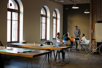 Creative business people working at tables in sunny office